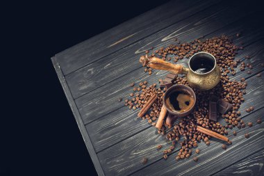 Eski kahve fincanı ve ahşap bir masada kavrulmuş fasulye ile Türk. Koyu arkaplanda klasik aroma kavramı.