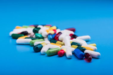 Mavi arka planda renkli haplar ve tıbbi kapsül