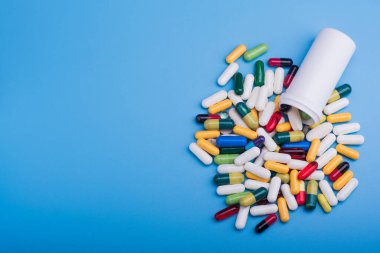 Mavi arka planda renkli haplar ve tıbbi kapsül
