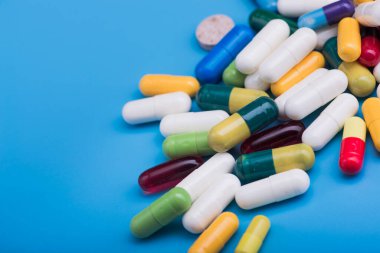 Mavi arka planda renkli haplar ve tıbbi kapsül