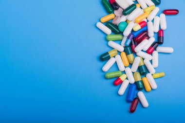 Mavi arka planda renkli haplar ve tıbbi kapsül