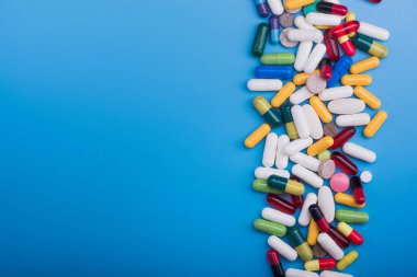 Mavi arka planda renkli haplar ve tıbbi kapsül