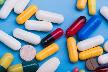 Mavi arka planda renkli haplar ve tıbbi kapsül