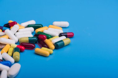 Mavi arka planda renkli haplar ve tıbbi kapsül