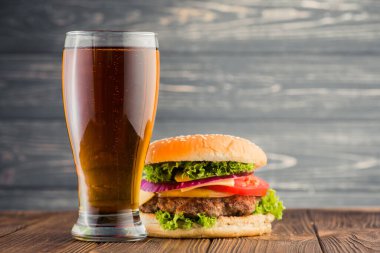 Lezzetli büyük hamburger ve bira bardağı ahşap masada