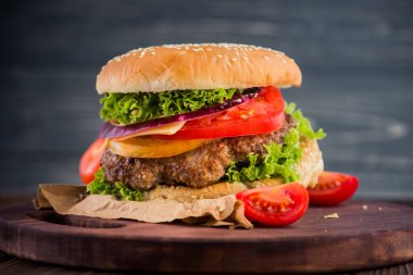 Domatesli ve ahşap masada sığır etli klasik burger. Fast food geçmişi