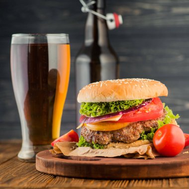Lezzetli büyük hamburger ve bira bardağı ahşap masada