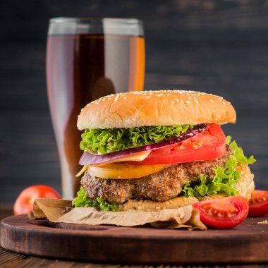 Lezzetli büyük hamburger ve bira bardağı ahşap masada