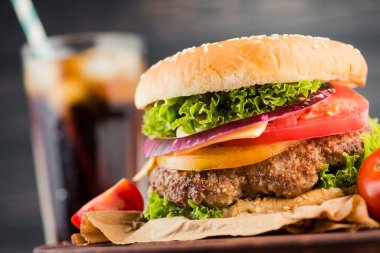 Amerikan aperatifi, büyük hamburger ve ahşap masada cam kola.