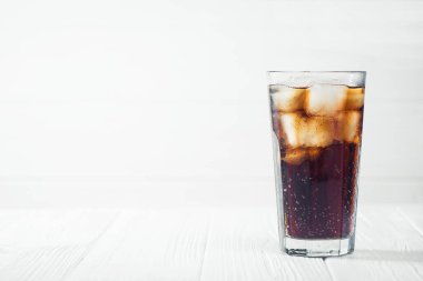 Beyaz ahşap masada buzlu kola bardağı.