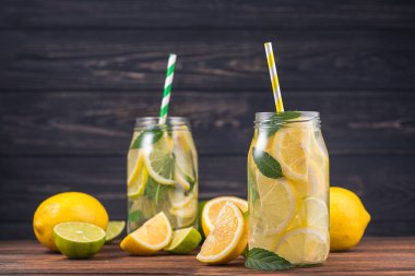 Limonlu limonata bardağı ve ahşap masada naneli meyve.