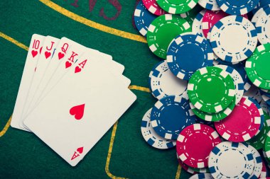 Kartlardaki kraliyet flaşı ve yeşil kumarhane masasındaki poker fişleri. Kumarda başarı