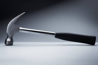 Beyaz masa üzerinde metal çekiç, siyah arkaplan üzerinde çalışma aracı