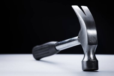 Beyaz masa üzerinde metal çekiç, siyah arkaplan üzerinde çalışma aracı
