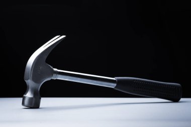 Beyaz masa üzerinde metal çekiç, siyah arkaplan üzerinde çalışma aracı