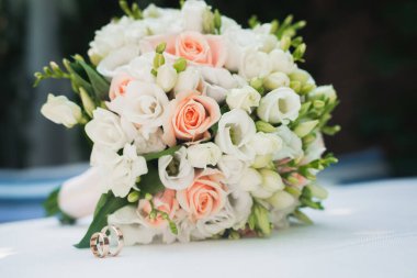 Düğün çiçeği buketi beyaz masada. Gül çiçeği süslemesi. Altın yüzükler