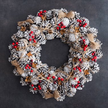 Çam kozalaklarıyla süslenmiş Noel çelengi, kar ve kırmızı böğürtlen, kış tatili