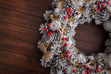 Çam kozalaklarıyla süslenmiş Noel çelengi, kar ve kırmızı böğürtlen, kış tatili