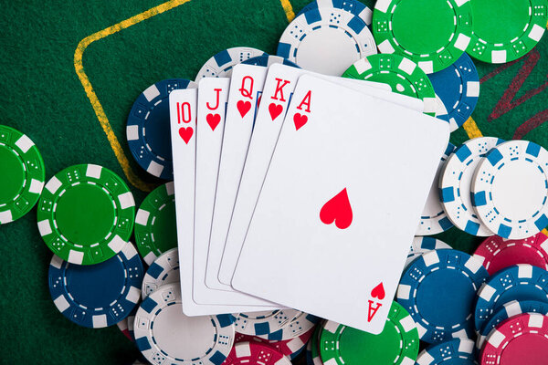 royal flash on cards and poker chips on green casino table. success in gambling