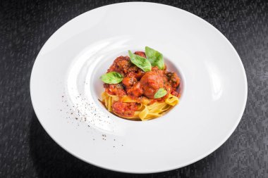 domates soslu makarna ve beyaz tabakta köfte.