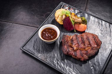 Siyah tahtada ızgara biftek ve sebze. Restoranda barbekü yemeği.