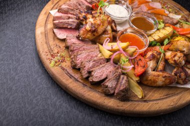 Tavuk budu, biftek, sebze ve soslu barbekü tahtası.