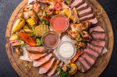 Tavuk budu, biftek, sebze ve soslu barbekü tahtası.