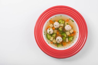 Brokolili lezzetli sebze çorbası ve beyaz arka planda izole edilmiş kırmızı tabakta tavuk topları. en üstteki görünüm