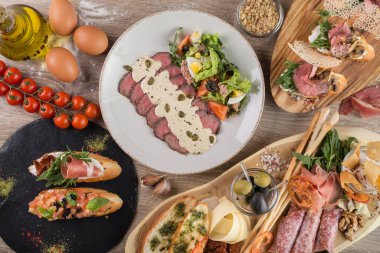 Domates ve mantarlı bruschetta 'dan abur cubur masası, soslu dana eti ve kapari. Yemek takımı. Üst görünüm.