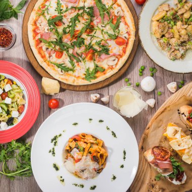 Pizza, makarna ve ahşap arka planda bruschetta 'dan öğle yemeği servisi. Yemek takımı, üst manzara..