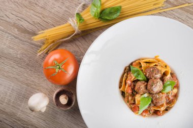 Beyaz tabakta köfteli taze makarna, ahşap masa. en üstteki görünüm
