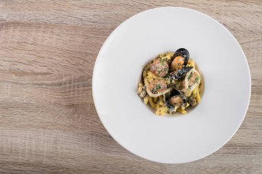 Beyaz tabakta midyeli makarna, deniz ürünleri arka planı.