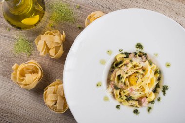 Beyaz tabakta çiğ yumurta ve ahşap masa ile lezzetli carbonara ezmesi. en üstteki görünüm