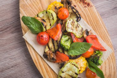 Taze ızgara domates, mantar, papper, mısır ve kabak tahtada. Sebzeli barbekü yemeği