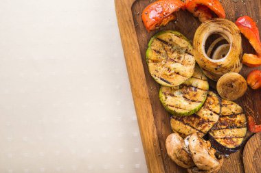 Ahşap bir tahtanın üzerinde ızgara sebze, patlıcan, kabak, mantar, biber, soğan. en üstteki görünüm