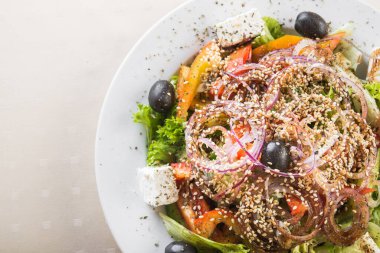 Taze yeşil salata, domates ve zeytin, beyaz tabakta beyaz peynir.