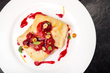 Beyaz tabakta ahududu ve şuruplu krep.