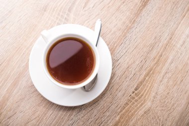 Tahta bir masada kaşıkla sıcak çay fincanı. en üstteki görünüm