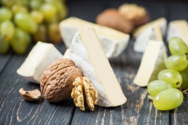 Tahta bir masada yeşil üzümlü ve cevizli beyaz camembert peyniri.