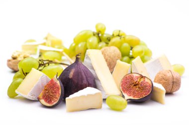 Beyaz arka planda, çerezler, üzümler, fındıklar ve incirlerden oluşan peynirli krema.