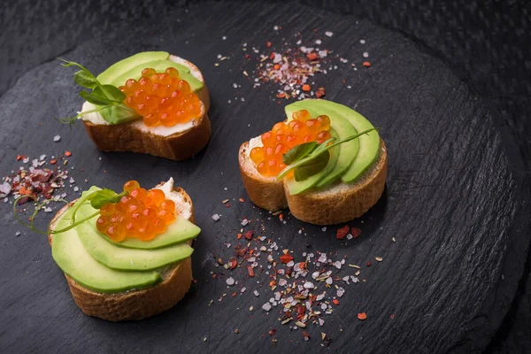 Sabrosa Bruschetta Con Aguacate Caviar Una Pizarra Negra Aperitivo Snack —  Fotos de Stock