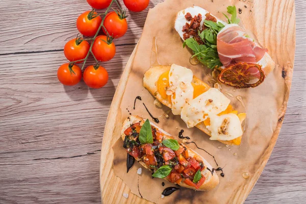 Vorspeisensnack Bruschetta Mit Tomate Schinken Und Basilikum Auf Einem Holzbrett — Stockfoto