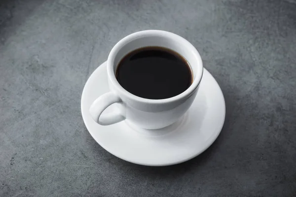石のテーブルの上に黒いコーヒーと白いセラミックカップ — ストック写真
