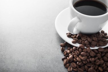 Taştan masa arkasında kavrulmuş fasulye olan beyaz kahve fincanı.