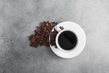 Taştan masa arkasında kavrulmuş fasulye olan beyaz kahve fincanı.