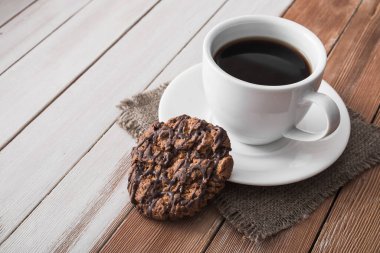 Tahta bir masada çikolatalı kurabiyeli kahve fincanı