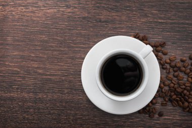 Beyaz kahve fincanı, siyah içecek, ahşap masa, üst manzara.