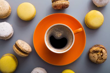 aroma kahve fincanı ve tatlı renkli badem kurabiyesi. Masada pasta, üst manzara.