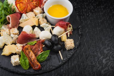 Peynir, jambonlu yemek ve domates, siyah tahta.