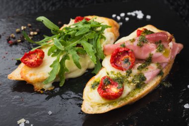 Domates ve pastırmalı aperatif bruschetta, siyah tahtada satranç.